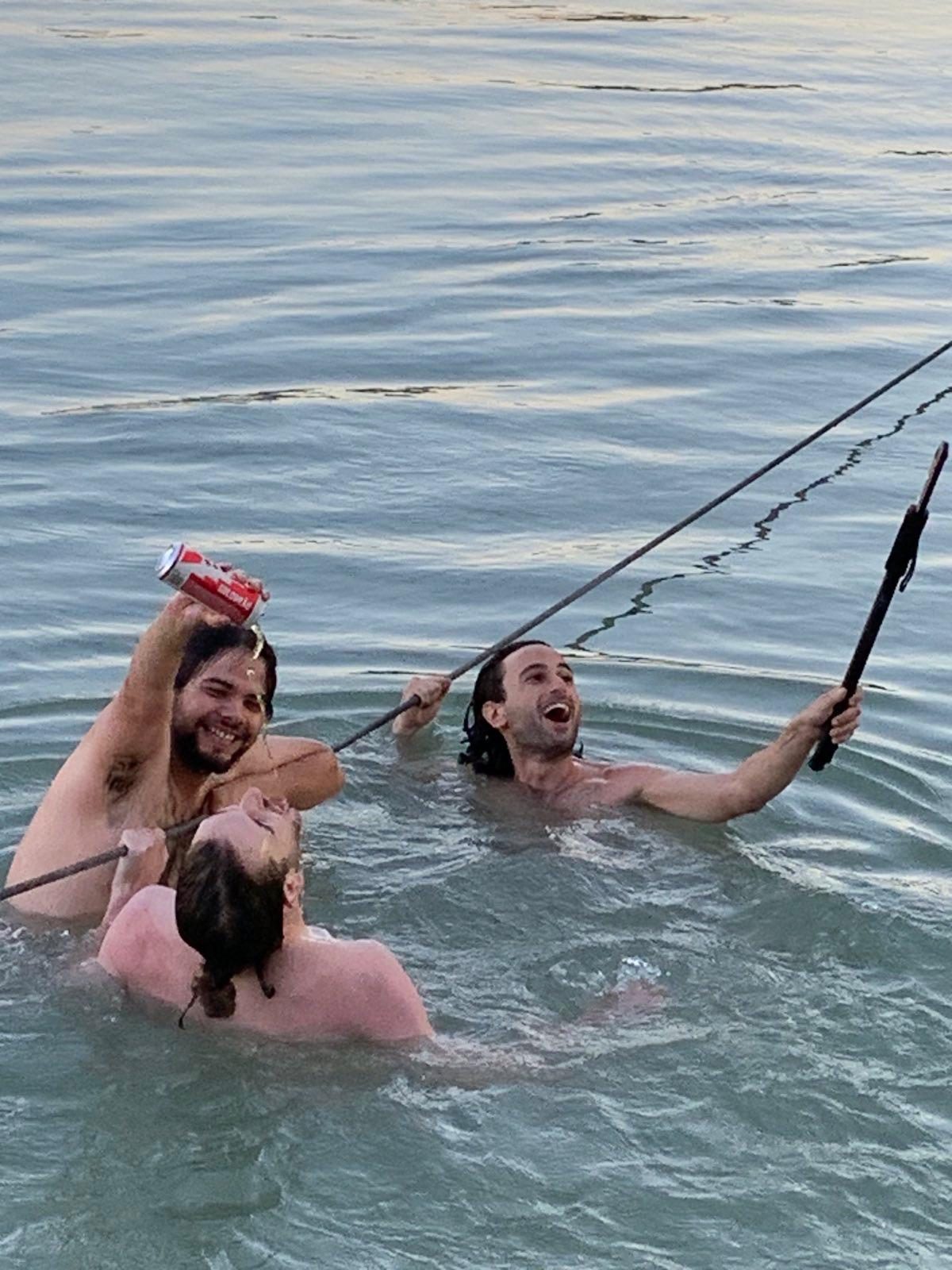 Apophenia: three people in a river, one holding a can and a fishing rod