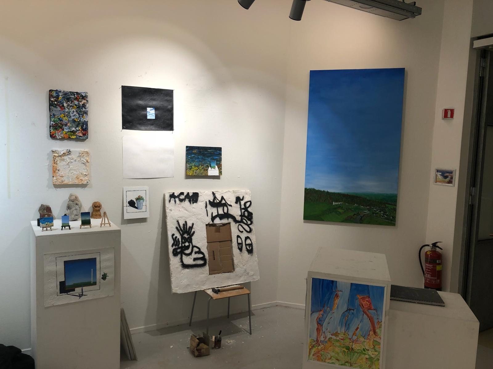Exhibition corner: the plaster wall on a chair with cardboard still in the hole, paintings around it